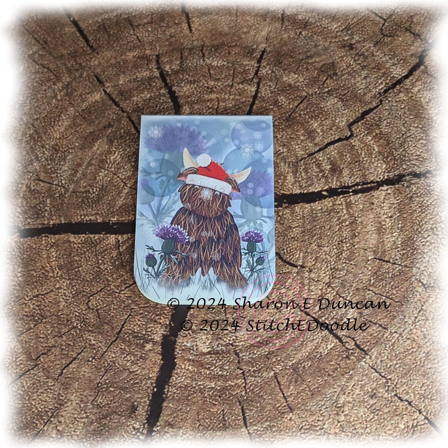 Highland Cow in Santa Hat with Thistles Double sided Laminated Magnetic Bookmark.  Original digital painting by Sharon Duncan.