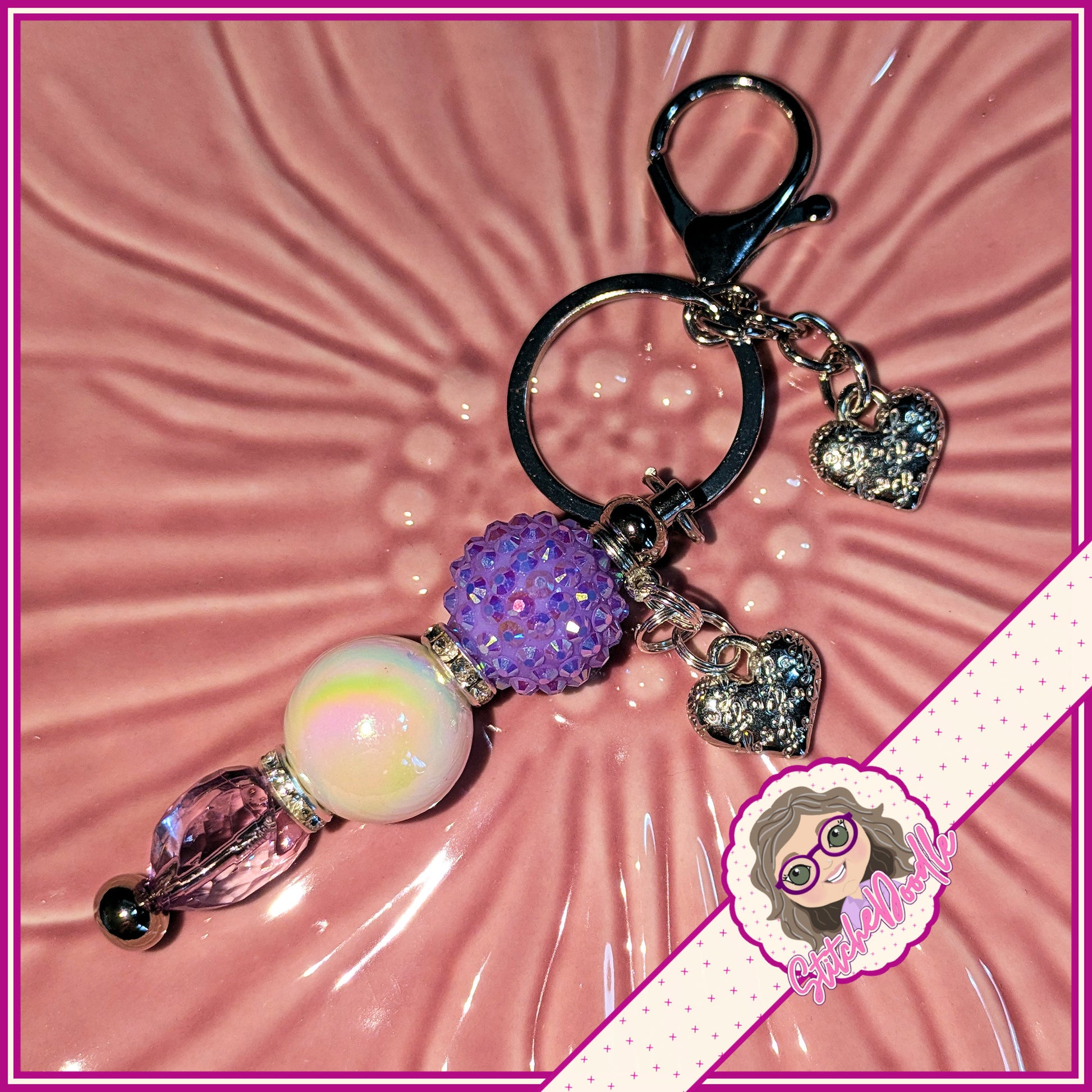 Decorative keychain with colorful beads and heart charms on a pink textured background