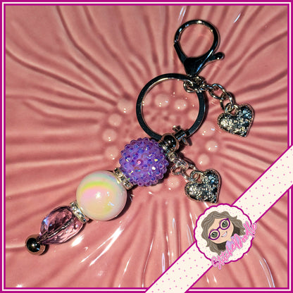 Decorative keychain with colorful beads and heart charms on a pink textured background